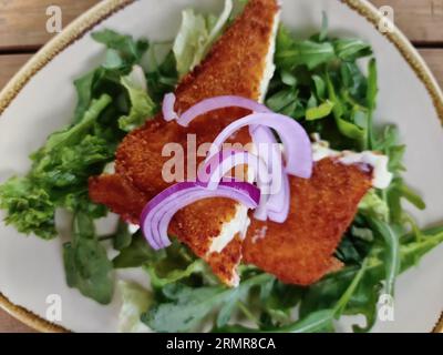 Fried Saganaki Cheese Served On A Plate With Green Salad Stock Photo