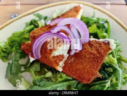 Fried Saganaki Cheese Served On A Plate With Green Salad Stock Photo