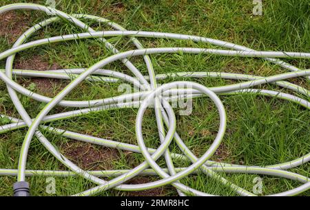 Top View Of Hosepipe On Grass And Cobblestone Surfaces. Minimalistic Conception. Stock Photo