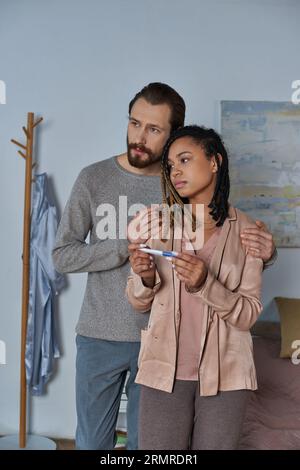 abortion concept, man hugging african american woman with pregnancy test, making decision, stress Stock Photo