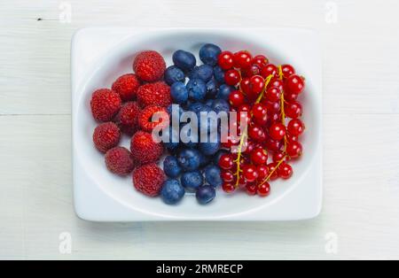 display of vibrant mixed berries, including raspberries, blueberries, and currants, adorns the rectangular container. Stock Photo