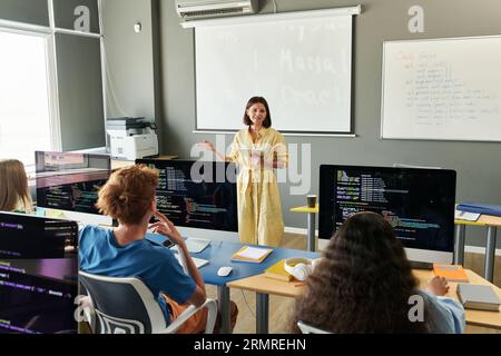 Teacher explaining material to students during IT lesson in the classroom Stock Photo