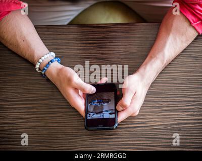 A person sitting at a table using a cell phone. Photo of a person using a cellphone at a table Stock Photo