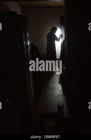 A lady, using a flashlight in her house, after the russian missile hit the Ukrainian electricity supply infrastructure Stock Photo