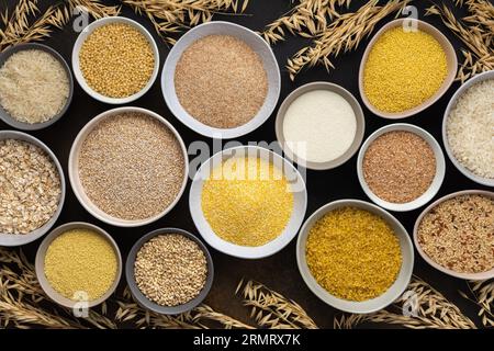 Various grain cereals in bowls, top view on a brown background with bowls of cereals and ears of oats Stock Photo