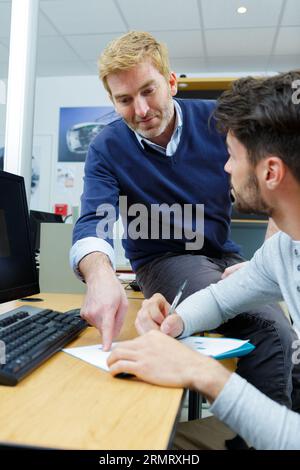teacher guiding young-adult to complete a form Stock Photo