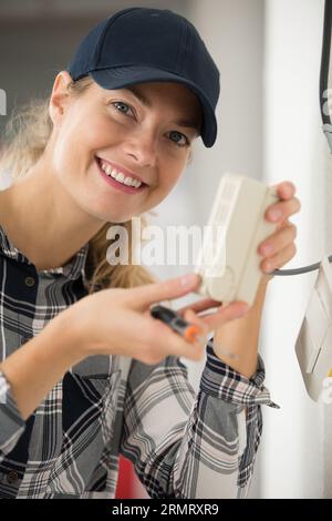 smiling female apprentice installing socket Stock Photo