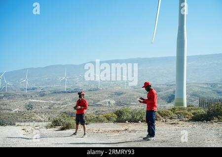 Engineers using virtual reality headset while working at windmill farm with tablet and drone - Renewable energy concept Stock Photo
