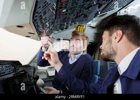 mechanic showing young men inside of cockpit Stock Photo