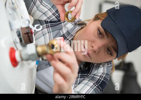 female technician servicing a boiler using tablet computer Stock Photo