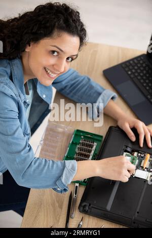 happy woman repairs a laptop using screw driver Stock Photo