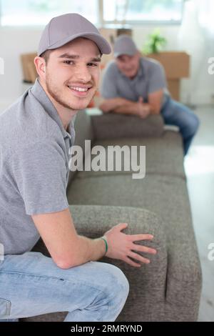 movers placing sofa on hardwood floor at home Stock Photo