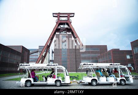 (230830) -- FRANKFURT, Aug. 30, 2023 (Xinhua) -- Tourists take electric sightseeing cars in the Zollverein coal mine industrial complex in Essen, Germany, Aug. 16, 2023.  From the Ruhr area in Germany to the Shougang industrial park in Beijing, one after another steel 'giants' stand as witnesses to the development process of human civilization.     The Ruhr area in Germany is a significant industrial zone in Europe, once a coal and steel production hub for Germany. The Zollverein coal mine industrial complex in Essen was one of the world's largest coal mines from the late 19th to the early 20t Stock Photo