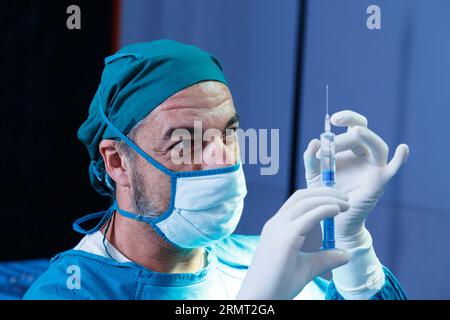 professional doctor holding general anesthetic medicine or antiviral drug vaccine needle syringe for patient before surgery in the operating room at t Stock Photo