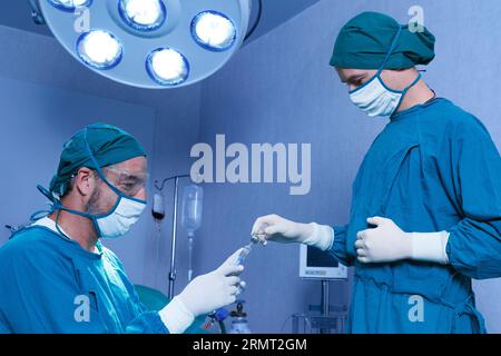 professional doctor holding general anesthetic medicine or antiviral drug vaccine needle syringe for patient before surgery in the operating room at t Stock Photo