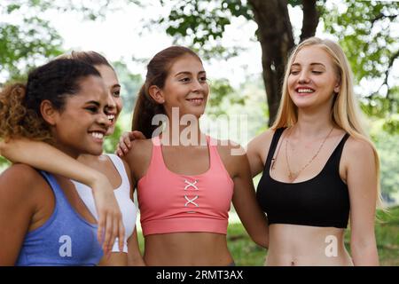 Happy smiling female friends. Woman talking and having fun in park after finish fitness yoga class exercise on weekend morning. Stock Photo