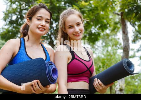 Happy smiling female friends. Woman talking and having fun in park after finish fitness yoga class exercise on weekend morning. Stock Photo