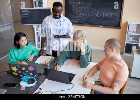 Team of highschool students brainstorming while preparing presentation of new project of decoding data or developing software at lesson Stock Photo
