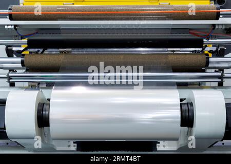 roll of plastic packaging film on the automatic packing machine in food product factory. industrial and technology concept. Stock Photo