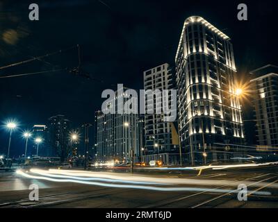 Low angle view of traffic on night city street. Light trails of cars driving by on street and night city illumination captured with long exposure. Bel Stock Photo