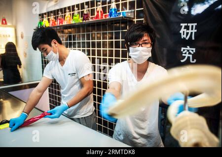 Chen Jingchao (R) and one of his apprentices pull malt sugar clumps to make hard candies at Yoo Candy in Beijing, capital of China, Aug. 29, 2014. As the candy chef of Yoo Candy, a confectioner s shop in Beijing s Nanluoguxiang, Chen Jingchao s job is to turn out fresh handmade sweets along with his apprentices. Formerly an IT professional in east China s Shanghai, the 24-year-old young man began to learn candymaking in 2013 and decided to pursue his career in Beijing this May. Yoo Candy s hit product is the Australian rock , a cylindrical hard candy with patterned design on its two ends. Chen Stock Photo