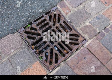 Cast-iron sewer grate on the sidewalk. Close up. Stock Photo