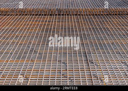Metal reinforcing cages laid for pouring the floors of a residential building with heating. View from above. Stock Photo
