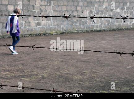 (140901) -- FRANKFURT (GERMANY), Sept. 1, 2014 -- A woman walks by the wire-bars at the site of former Sachsenhausen Nazi concentration camp in Oranienburg, near Berlin, Germany, on Aug. 21, 2014. The Sachsenhausen Nazi concentration camp was built in Oranienburg about 35 km north of Berlin in 1936 and imprisoned about 220,000 people between 1936 and 1945. The site now served as a memorial and museum to learn about the history within the authentic surroundings, including the remnants of buildings and other relics of the camp. ) GERMANY-SACHSENHAUSEN CONCENTRATION CAMP luoxhuanhuan PUBLICATIONx Stock Photo