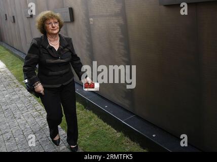 (140902) -- SHANGHAI, Sept. 2, 2014 -- Sonja Muehlberger walks along a copper wall at the Shanghai Jewish Refugee Museum, in Shanghai, east China, Sept. 2, 2014. A list naming 13,732 Jewish refugees who took safe haven in China during World War II carved into the 34-meter-long copper wall was unveiled at the museum on Tuesday. Sonja, 75, a German activist who was born into a Jewish family in Shanghai in 1939. Names of her family were also on the list, which originated from the appendix of Exile in Shanghai:1938-1947, a German book exploring the time period. Sonja contributed to the book and pr Stock Photo