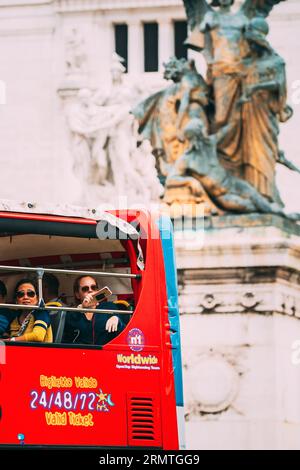 Rome, Italy. Tourists In Red Hop On Hop Off Touristic Bus For Sightseeing In Street Near Altar Of The Fatherland On Piazza Venezia. Famous World Stock Photo