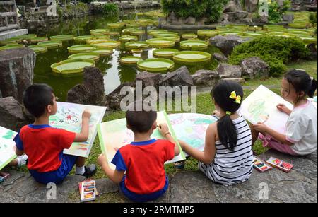 (140911) -- TAIPEI, Sept. 11, 2014 -- Children paint giant leaves of Victoria during an aquatic plants exhibition at the Shuangxi Park in Taipei, southeast China s Taiwan, Sept. 11, 2014. Victoria is a genus of water-lilies, in the plant family Nymphaeaceae, with very large green leaves that lie flat on the water s surface. The leaf of Victoria is able to support quite a large weight due to the plant s structure, although the leaf itself is quite delicate. )(yxb) CHINA-TAIPEI-SHUANGXI PARK-VICTORIA-GIANT LEAF (CN) WangxQingqin PUBLICATIONxNOTxINxCHN   Taipei Sept 11 2014 Children Paint Giant L Stock Photo
