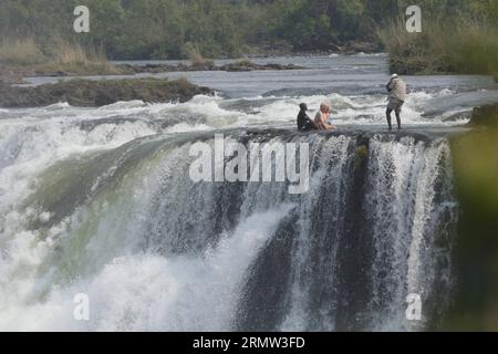 (141002) -- VICTORIA FALLS, -- Foreign tourists pose for photos with local guides at the devil s pool on top of the Victoria Falls, on the borders of Zimbabwe and Zambia, Sept. 30, 2014. The devil s pool is a major site for tourists to the Victoria Falls during the dry season, especially for the months of September and October when the water levels are at the lowest and the current of the Zambezi River is mild. Protected only by the instruction of local guides, swimming in the pool, located on the verge of the 108-meter-high Victoria Falls, has been described as one of the most exciting touris Stock Photo