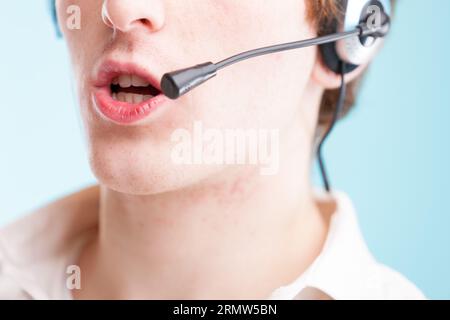 When you think 'contact us,' picture this: close-up of a young man's lips to neck, speaking into a headset. Wearing a white shirt, representing custom Stock Photo