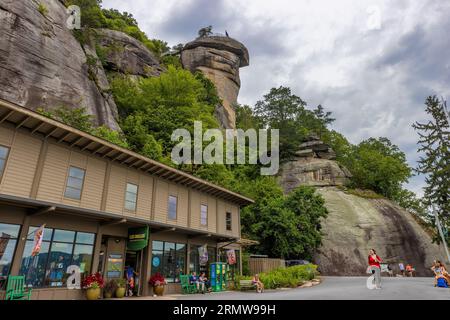 Chimney Rock, North Carolina, USA - August 11, 2023:Chimney Rock towers over people and gift shop below at Chimney Rock State Park. Stock Photo