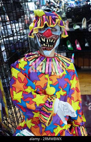 A mannequin wearing a colorful clown costume and a scary rubber mask. Inside the Halloween Adventure on Broadway in Greenwich Village. Stock Photo