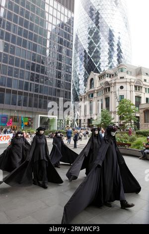 London, UK. 30th Aug, 2023. Extinction Rebellion protestors targeted 10 insurance firms in the City of London, urging them not to insure the East Africa Crude Oil Pipeline (EACOP). 'Oil Slickers' in black and white facepaint marched silently through the streets and outside each insurance firm symbolic (fake) oil was poured over a globe before being cleaned up by a team in hazmat suits. Credit: Anna Watson/Alamy Live News Stock Photo