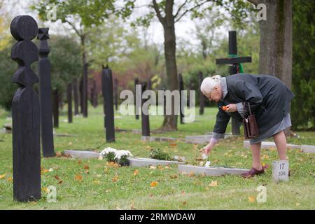 (141023) -- BUDAPEST, Oct. 23, 2014 -- A woman lights a candle in memory of her friend in a cemetery on national holiday commemorating the revolution of 1956 in Budapest, Hungary on Oct. 23, 2014. Hungarians marked Thursday with a series of events remembering the failed 1956 revolution that began on Oct. 23, exactly 58 years ago. ) HUNGARY-BUDAPEST-REVOLUTION-COMMEMORATION AttilaxVolgyi PUBLICATIONxNOTxINxCHN   Budapest OCT 23 2014 a Woman Lights a Candle in Memory of her Friend in a Cemetery ON National Holiday Commemorating Ting The Revolution of 1956 in Budapest Hungary ON OCT 23 2014 Hunga Stock Photo