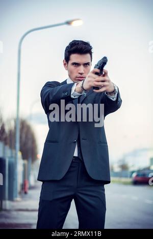 Photo of a man holding a firearm in a formal attire Stock Photo