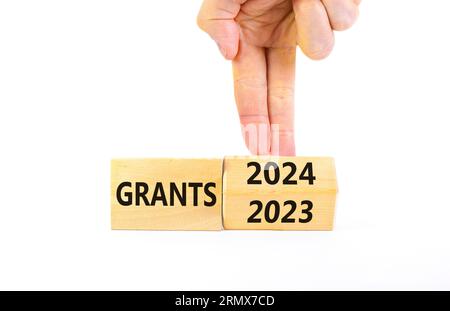 Planning 2024 grants new year symbol. Businessman turns a wooden cube and changes words Grants 2023 to Grants 2024. Beautiful white background, copy s Stock Photo