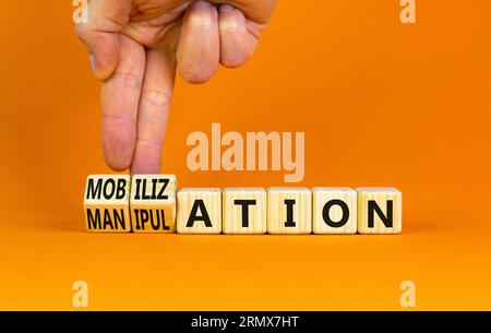 Mobilization or manipulation symbol. Concept words Mobilization Manipulation on wooden cubes. Beautiful orange background. Psychologist hand. Psycholo Stock Photo