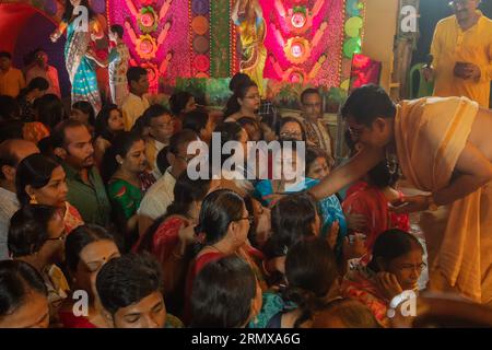 Howrah,West Bengal,India- 3rd October, 2022 : Hindu purohit drawing tilak, holy sign on forehead of Hindu devotees worshipping Goddess Durga. Stock Photo