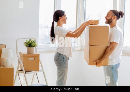 Happy young spouses packing boxes, moving, relocating to new apartment Stock Photo