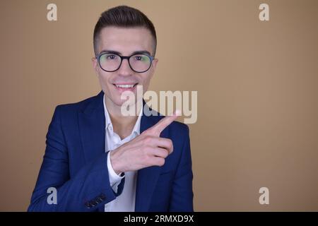 Smiling Young Handsome Elegant Man Pointing Finger to the Side at Copy Space on Isolated Background Stock Photo