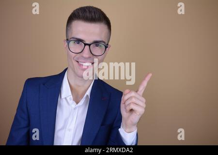 Smiling Young Handsome Elegant Man Pointing Finger to the Side at Copy Space on Isolated Background Stock Photo