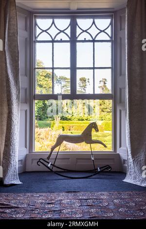 Rocking horse in open window of 18th century flower loft conversion near Penzance in Cornwall, UK Stock Photo