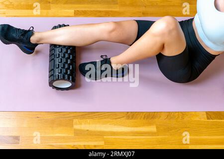 High angle view of female athlete using foam roller massaging her leg. Myofascia release, fascial, increasing flexibility of muscles. Stock Photo