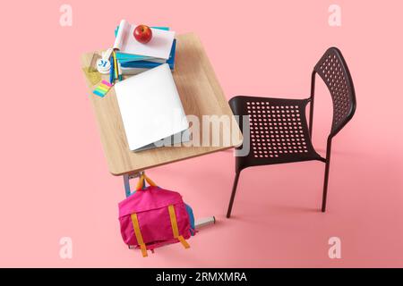 Modern school desk with backpack, laptop and stationery on pink background Stock Photo