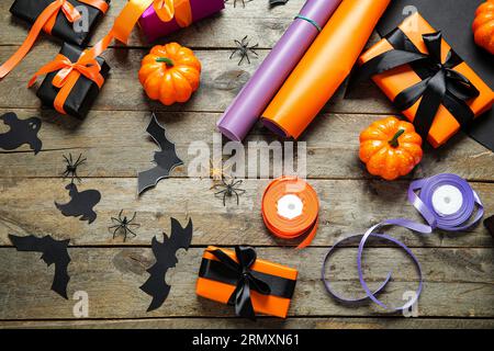 Halloween decorations with gift boxes, wrapping paper and ribbons on brown wooden background Stock Photo