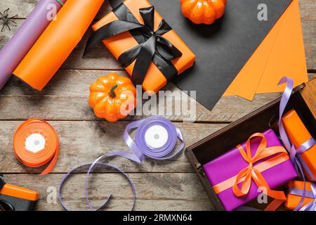 Halloween decorations with gift boxes, wrapping paper and ribbons on brown wooden background Stock Photo