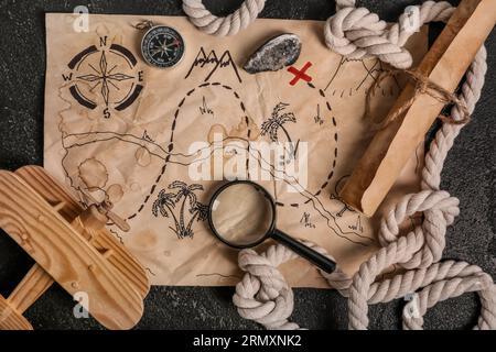 Treasure map with travel equipment, toy airplane and golden nuggets on black background Stock Photo